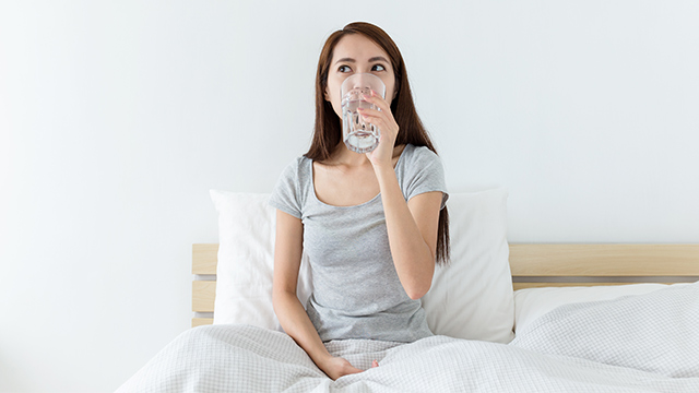 Mulher sorrindo no parque tomando agua e fazendo exercicios