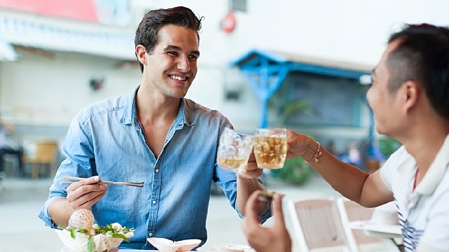dois amigos fazendo brinde durante almoço