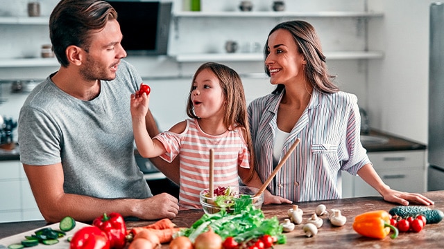 Pais incentivando alimentação saudável na filha