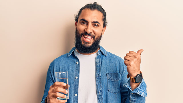 Homem com boca seca, segurando um copo de água e sorrindo
