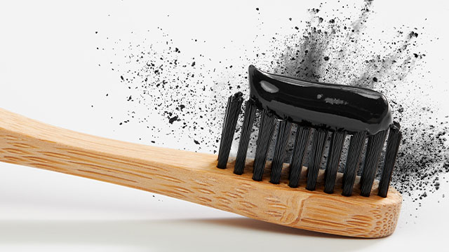 Escova de dente de madeira com pasta de dente carvão ativado colgate em cima das cerdas