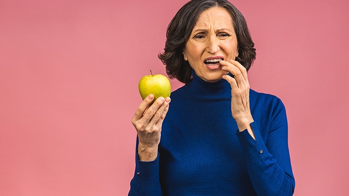 Mulher com a mão nos dentes porque está sentindo dor