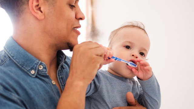 Pai escovando dentes de bebê