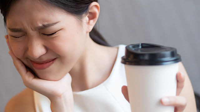 Mulher tomando café e com dor de dente