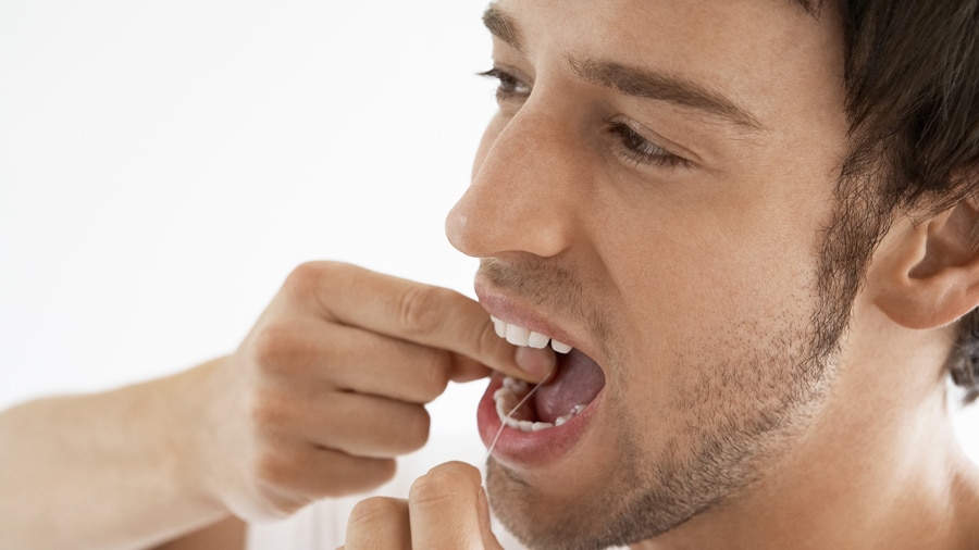 jovem usando fio dental nos dentes
