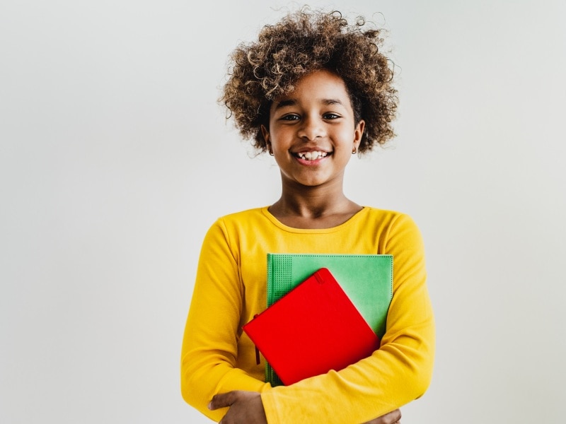 Garoto segurando seu material escolar novo na volta às aulas