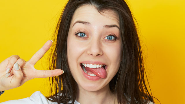 Mulher sorrindo com a língua pra fora depois de tratar mancha preta na língua