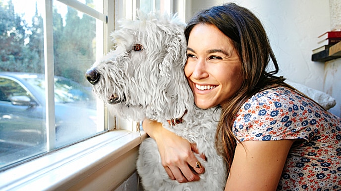 mulher sorrindo abraçada ao seu cão