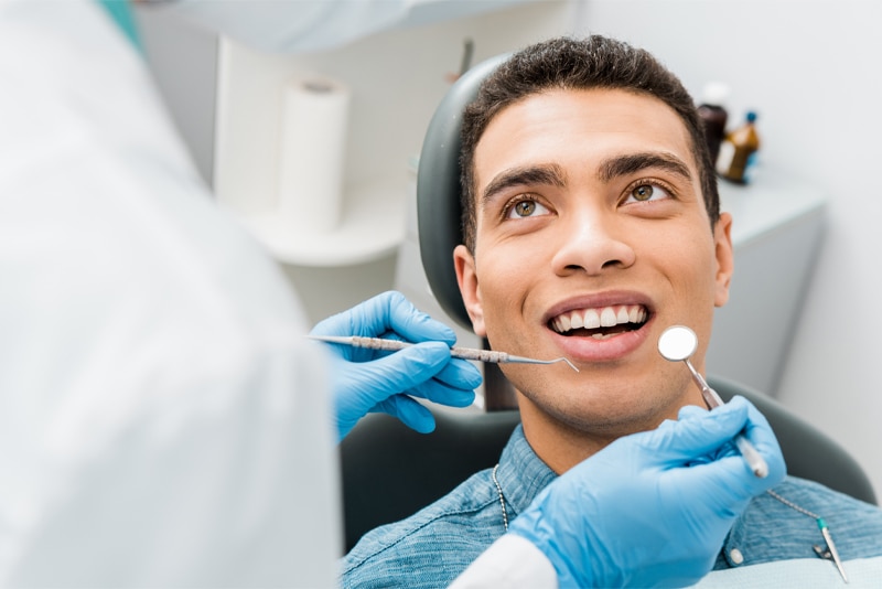 Dentista no consultório explicando sobre o tratamento de cárie para o paciente